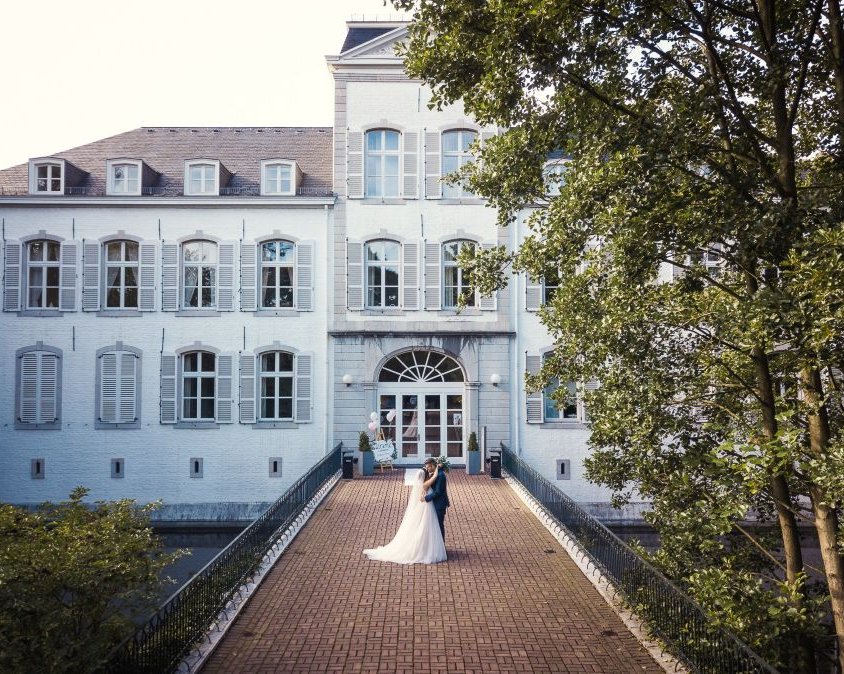 Außenansicht von Schloss Rahe in Aachen mit einem Brautpaar auf der Brücke