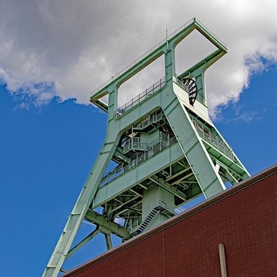 Das markante grüne Fördergerüst des Deutschen Bergbau-Museums vor blauem Himmel in Bochum
