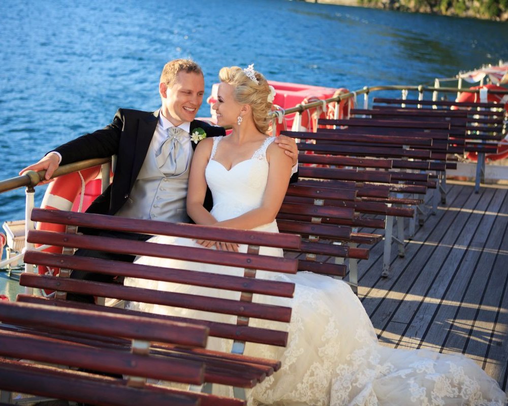 Ein Brautpaar sitzt entspannt auf dem Sonnendeck eines großen Schiffes und genießt die Aussicht aufs Wasser
