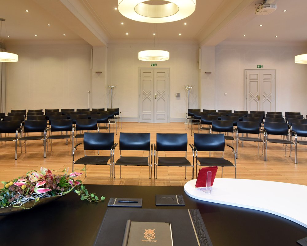 Der weitläufige Bürgersaal im Rathaus Karlsruhe-Durlach mit Blick vom Trautisch auf die Stuhlreihen für Gäste – ideal für größere standesamtliche Trauungen.