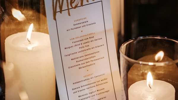 Menükarte und Kerzen als stilvolle Hochzeitsdetails in der Hochzeitslocation E210 Eventhangar in Rheinmünster
