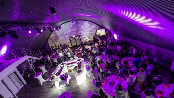 Gesamtansicht einer Hochzeitsfeier mit Gästen und Lichtkonzept in der Hochzeitslocation E210 Eventhangar in Rheinmünster