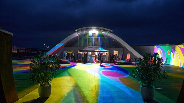 Spektakuläre Außeninszenierung bei Nacht mit farbigem Lichtkonzept an der Hochzeitslocation E210 Eventhangar in Rheinmünster