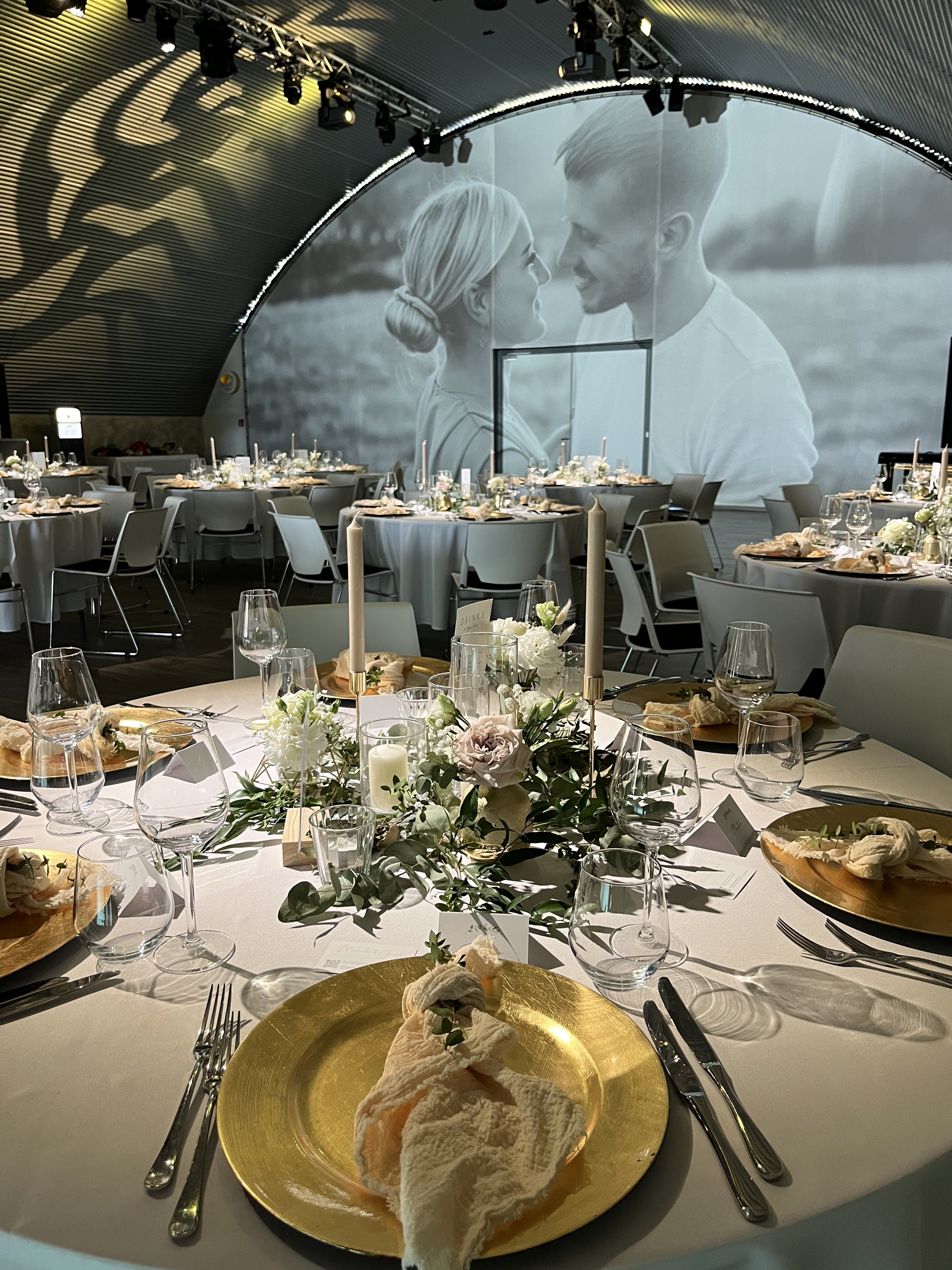 Festlich gedeckte Hochzeitstische mit Videowall in der Hochzeitslocation E210 Eventhangar in Rheinmünster