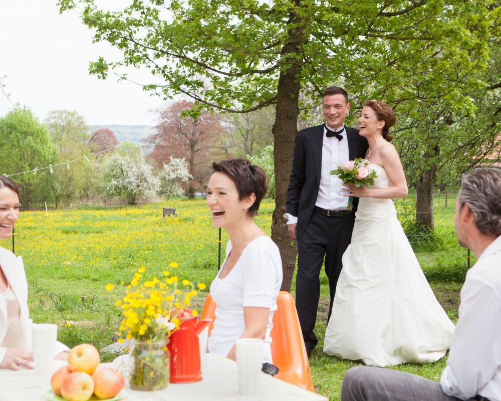 Entspanntes und glückliches Hochzeitspaar beim Sektempfang im Grünen