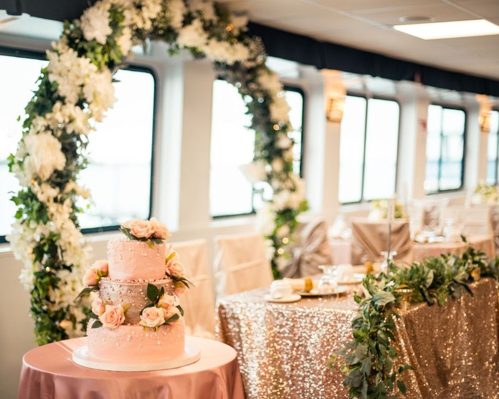 Innenraum eines Hochzeitsschiffs mit floraler Deko, runder Hochzeitstorte und feierlich gedeckten Tischen