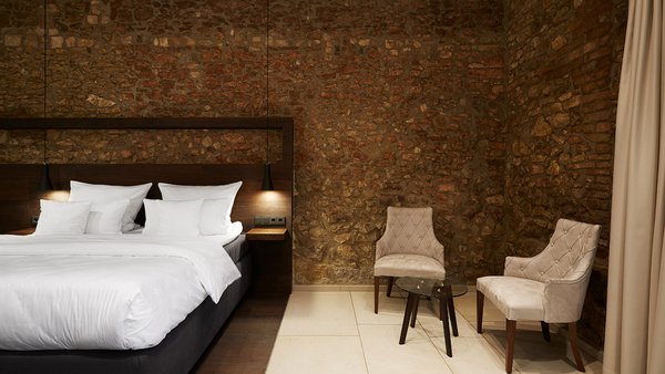 Modernes Hotelzimmer in Westhofen mit freigelegtem Fachwerk und Natursteinwand.
