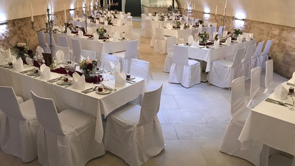 Romantisches Ambiente mit weißen Stuhlhussen im historischen Gewölbekeller von GUT LEBEN am Morstein.