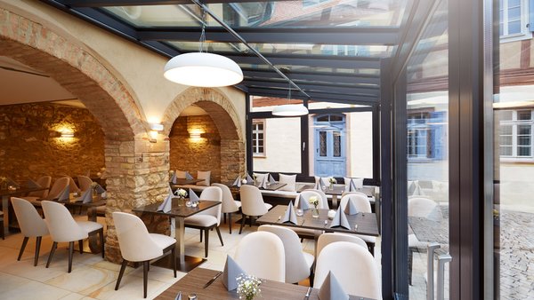 Moderner Gastraum „Remise“ der Hochzeitslocation GUT LEBEN am Morstein mit großen Glasfronten und rustikalem Flair.