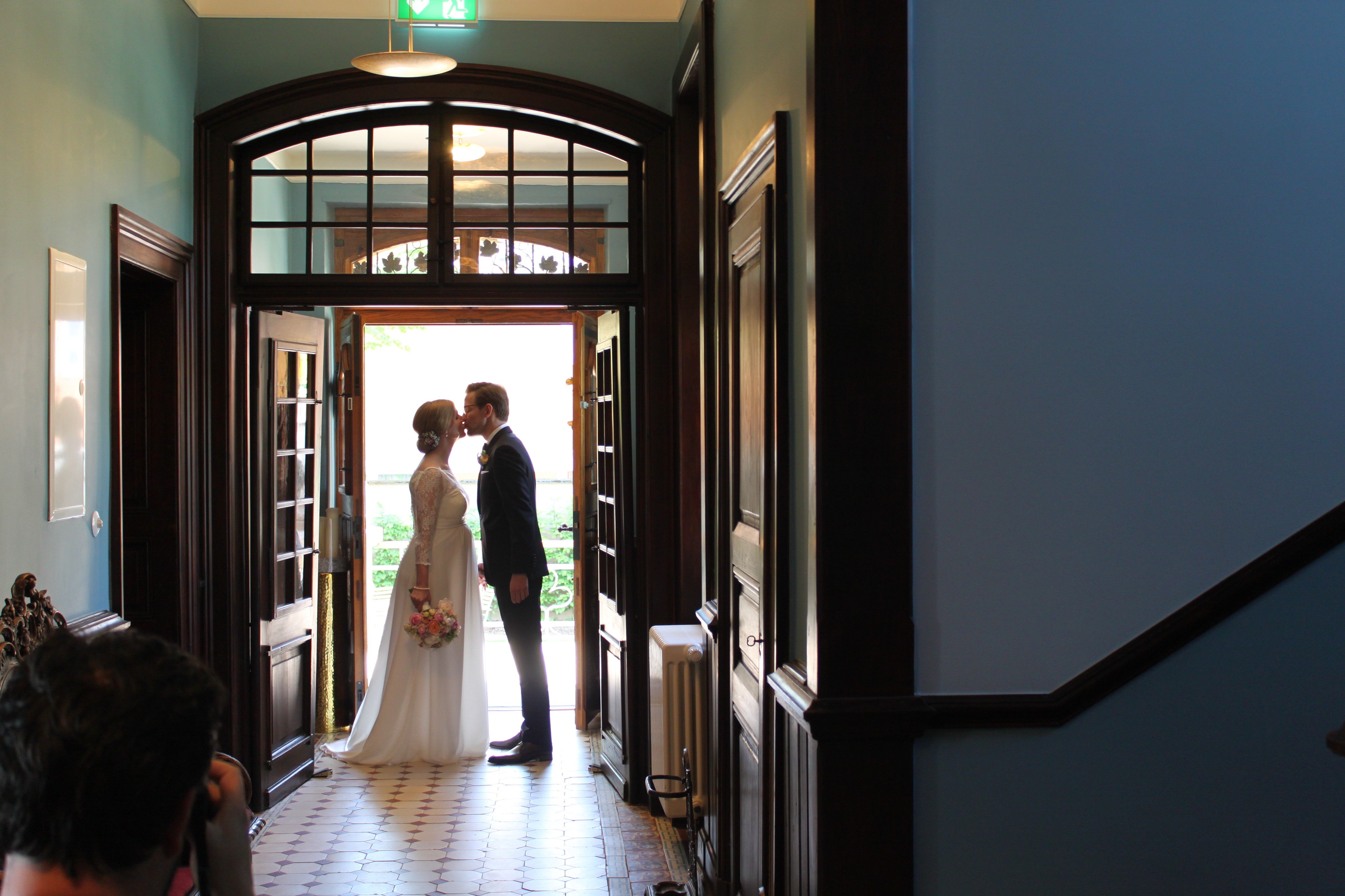 Romantisches Brautpaar-Shooting im GUT LEBEN am Morstein: Ein küssendes Paar im Gegenlicht vor dem historischen Rundbogenportal der Villa in Westhofen.