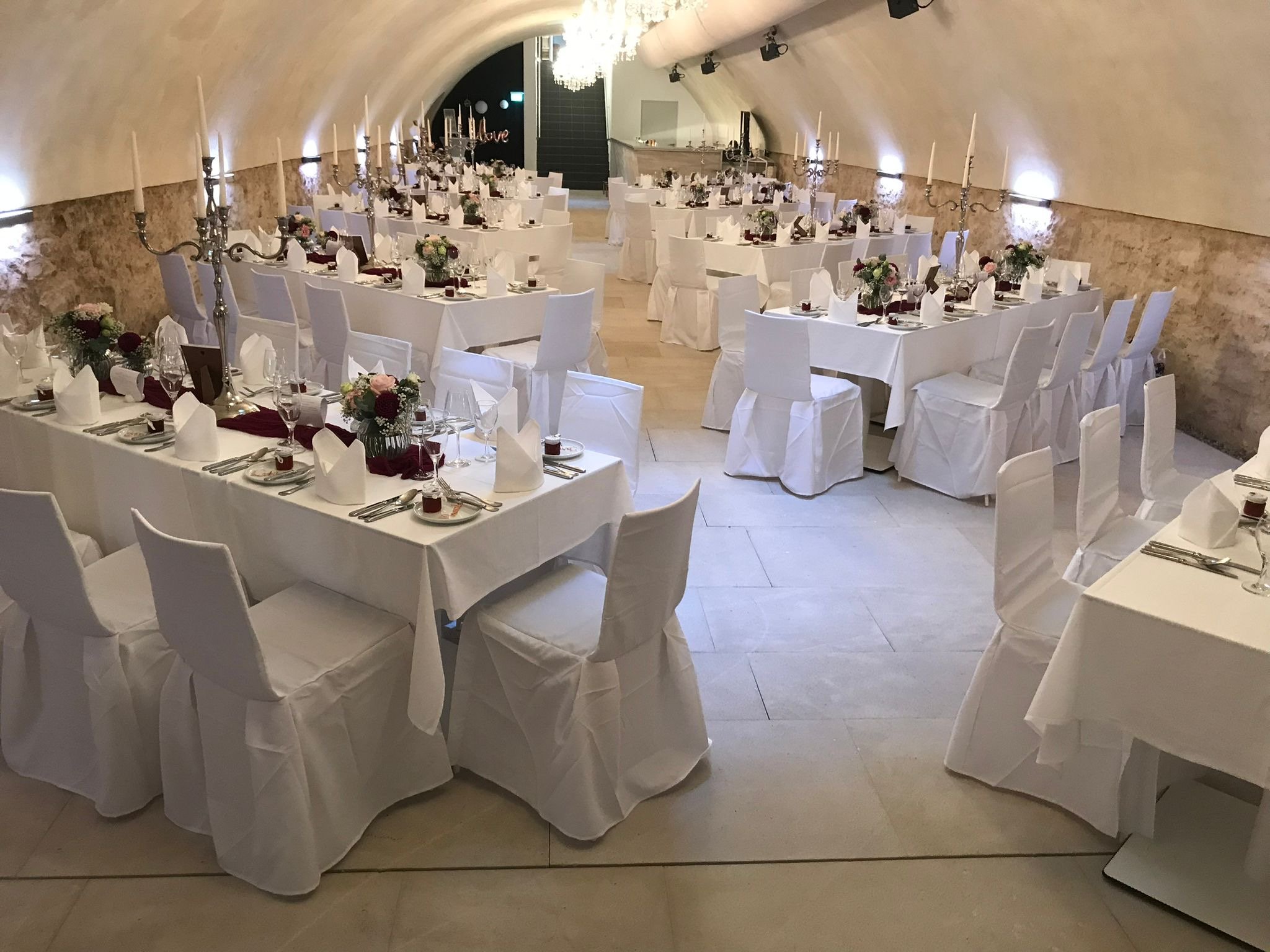 Romantisches Ambiente mit weißen Stuhlhussen im historischen Gewölbekeller von GUT LEBEN am Morstein.