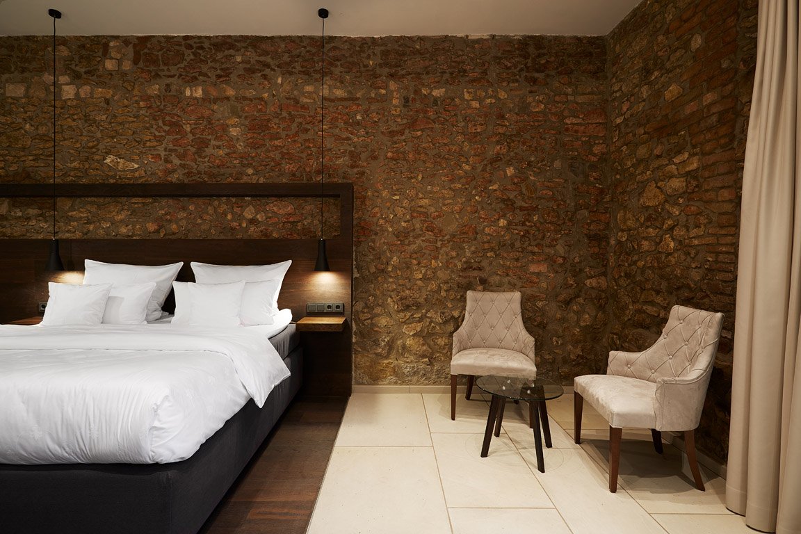 Modernes Hotelzimmer in Westhofen mit freigelegtem Fachwerk und Natursteinwand.