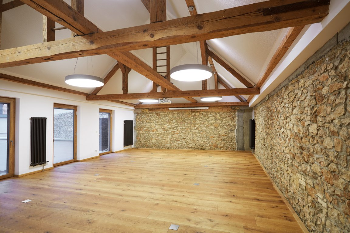 Heller Raum für Hochzeitsfeiern im GUT LEBEN am Morstein mit freigelegten Steinwänden und Holzbalken.