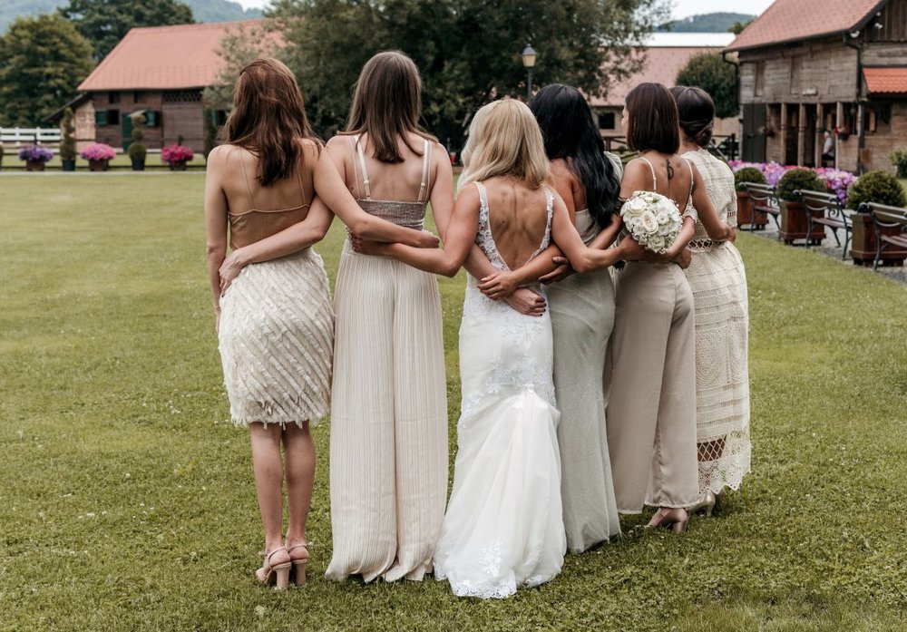 Die Braut steht mit Brautjungfern auf einer Wiese bei einer Hochzeit auf dem Land