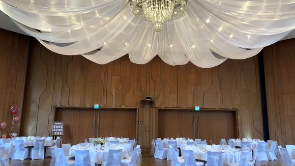 Großer Hochzeitssaal im Kurhaus Bad Krozingen mit weißen Stuhlhussen und Stoffbahnen – romantische Hochzeitslocation bei Freiburg.