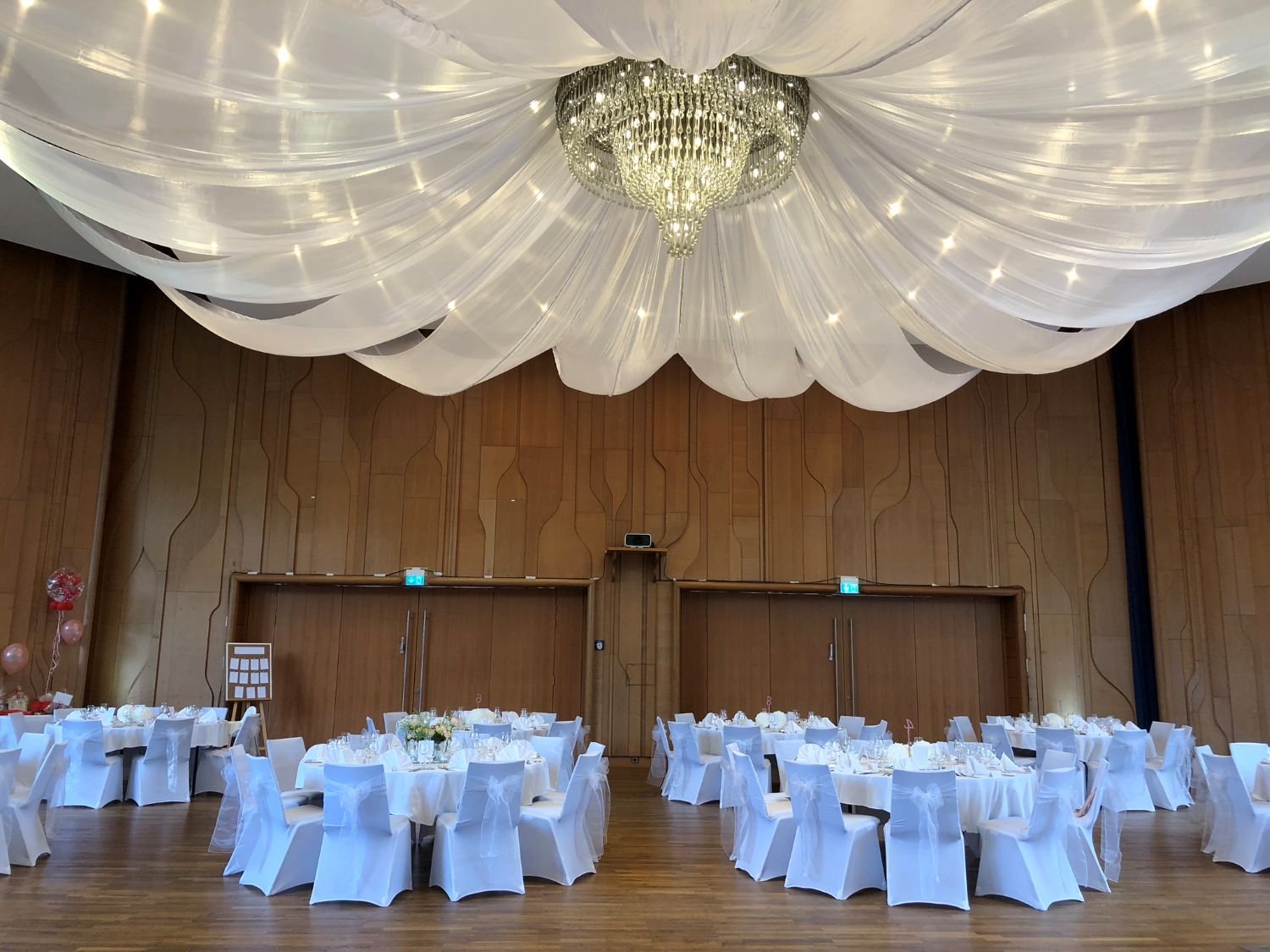 Großer Hochzeitssaal im Kurhaus Bad Krozingen mit weißen Stuhlhussen und Stoffbahnen – romantische Hochzeitslocation bei Freiburg.