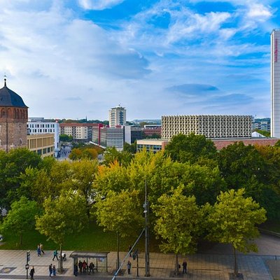 Hochzeit in Chemnitz: Blick über den grünen Theaterplatz mit dem Opernhaus und modernen Stadtgebäuden bei blauem Himmel.