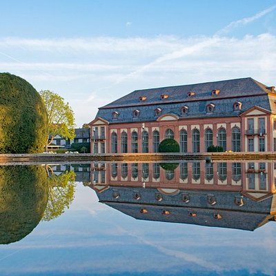 Historisches Orangerie-Gebäude in Darmstadt-Bessungen, das sich an einem sonnigen Tag im Teich spiegelt.