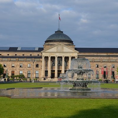 Prachtvolles Kurhaus Wiesbaden mit Kuppel, Säulen und einer großen Fontäne auf der Wiese davor.