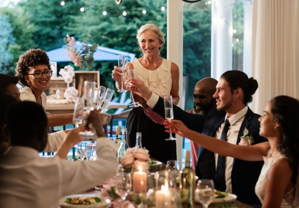 Entspanntes Hochzeitswochenende - Gäste stoßen beim gemeinsamen Hochzeitsessen auf das Brautpaar an