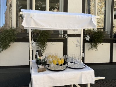 Kleines Wägelchen mit Sektgläsern vor dem historischen Fachwerkhaus des Hotel-Restaurant Burbaum