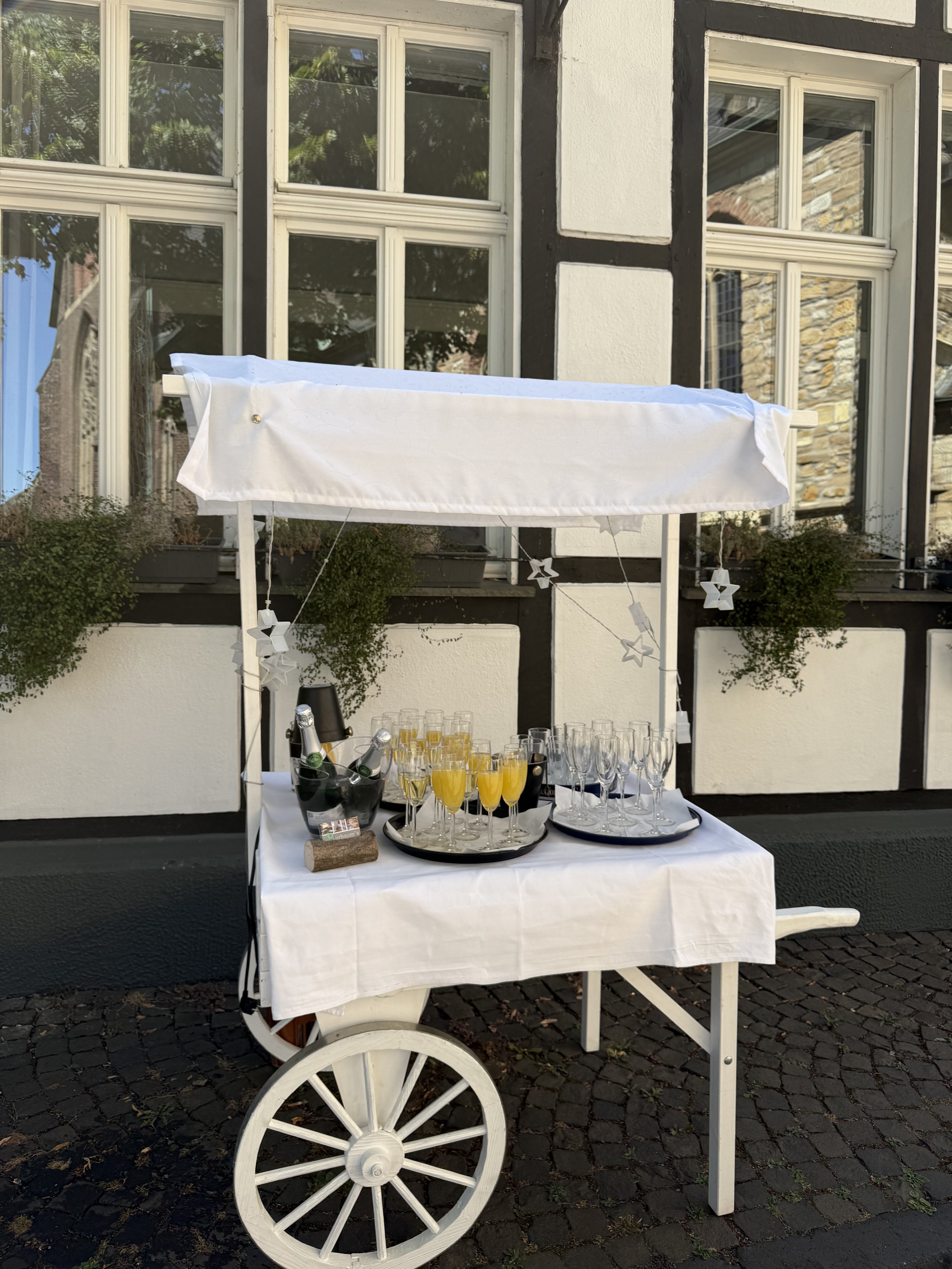 Kleines Wägelchen mit Sektgläsern vor dem historischen Fachwerkhaus des Hotel-Restaurant Burbaum