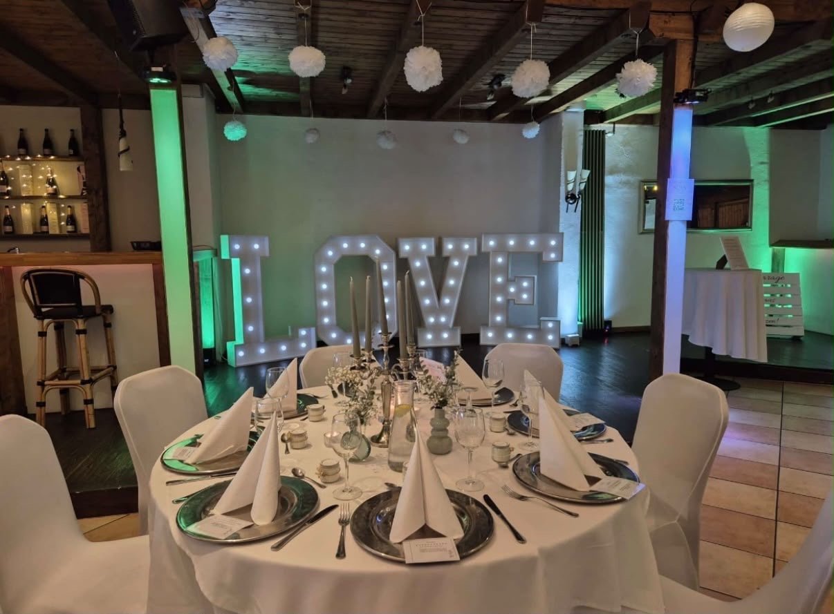 Festlich gedeckter Hochzeitstisch und leuchtende LOVE-Deko in der Hochzeitslocation