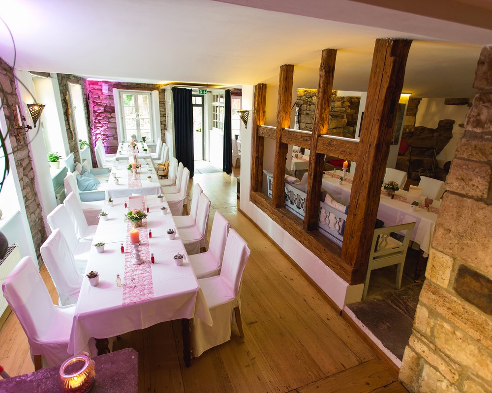 Festlich gedeckte lange Tafel mit weißen Stuhlhussen und rosa Tischläufern in einem rustikal-gemütlichen Veranstaltungsraum der Villa Lina in Bad Herrenalb.