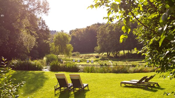 Gartenanlage der Hochzeitslocation Landhaus Bärenmühle mit Blick ins Grüne und Liegen