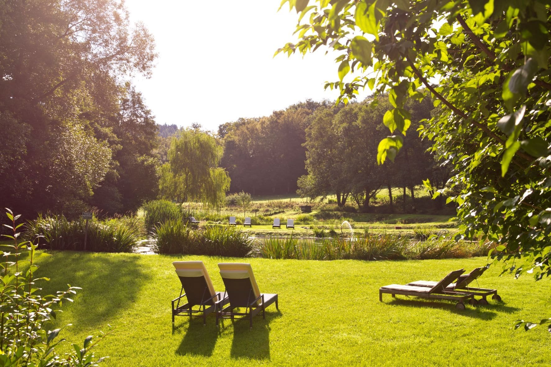 Gartenanlage der Hochzeitslocation Landhaus Bärenmühle mit Blick ins Grüne und Liegen
