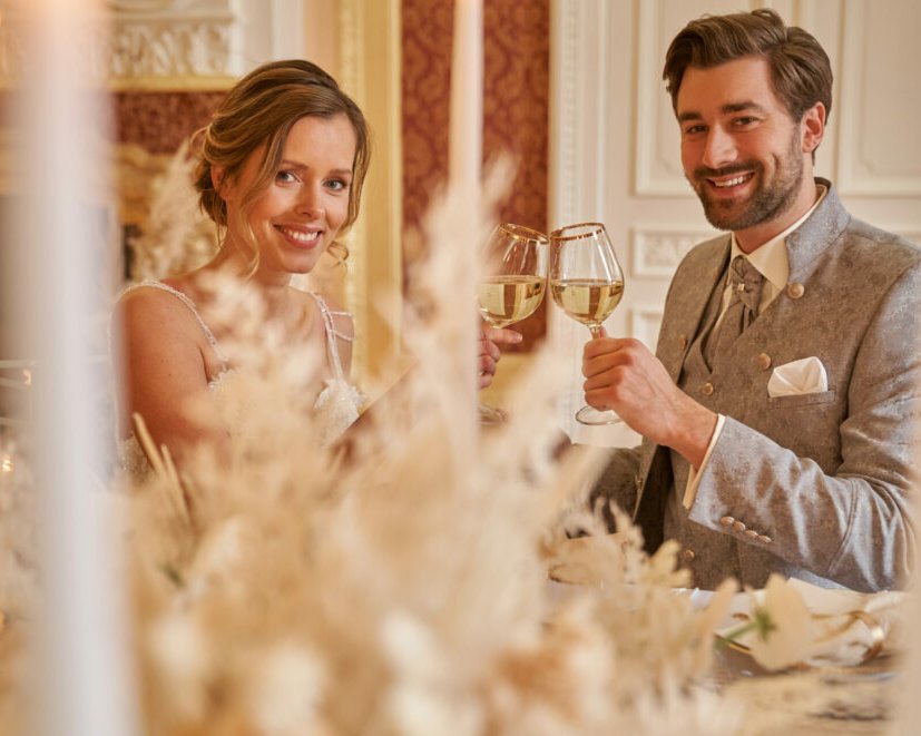 Braut und Bräutigam stoßen beim Hochzeitsempfang im Schloss Hohenprießnitz am festlich gedeckten Tisch an