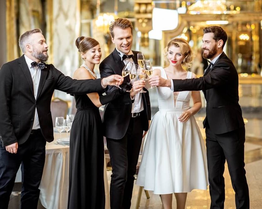 Brautpaar stößt mit Hochzeitsgästen im festlich geschmückten Schloss-Saal an