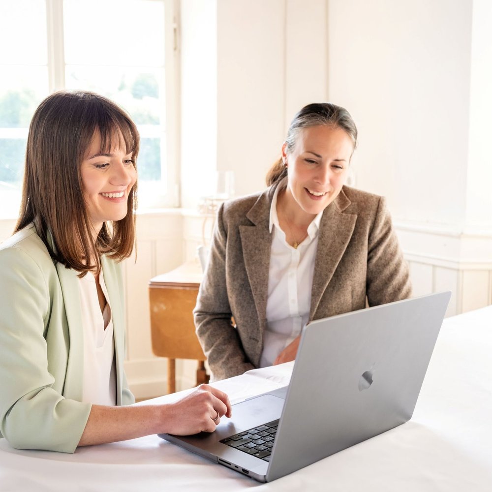 Unserehochzeitslocation.de hilft Hochzeitslocations, online sichtbarer zu werden – zwei Frauen besprechen am Laptop die Optimierung des Location-Profils