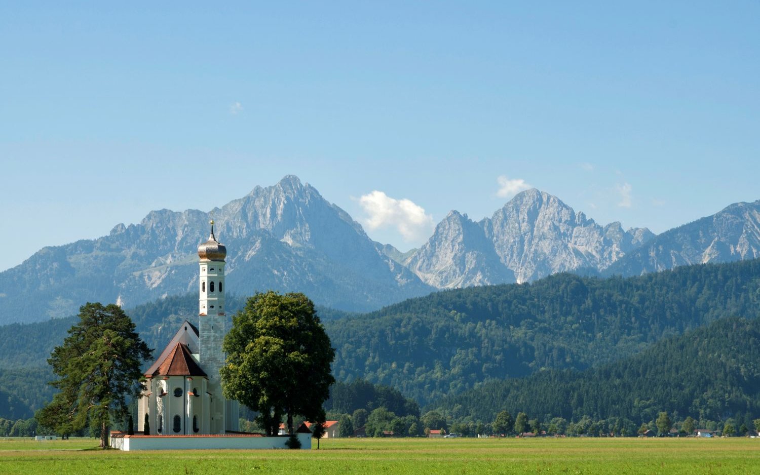 Historische Kirche St. Coloman vor einer beeindruckenden Alpenkulisse in Bayern