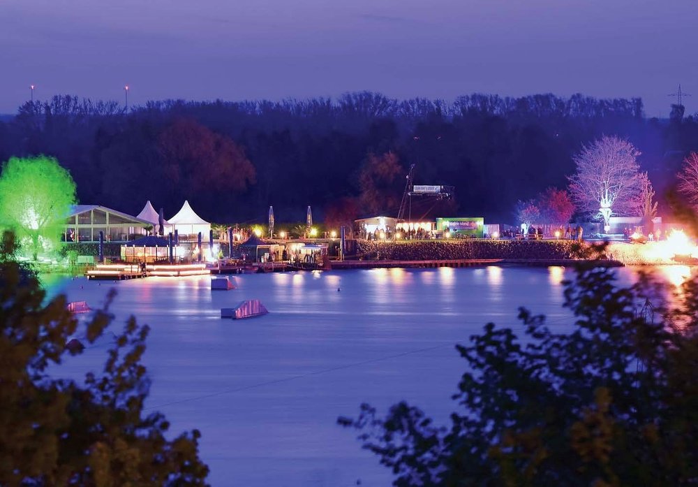 Blick über den See und den Steg im STRANDPARX Magdeburg am Abend.