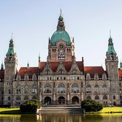 Sonnige Außenansicht des Neuen Rathauses in Hannover mit Parkanlage.